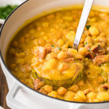 A pot of Spanish bean soup with a ladle removing a scoop.