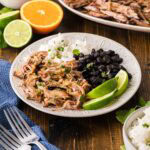 A plate with a serving of Mojo, pork, black beans, and rice.