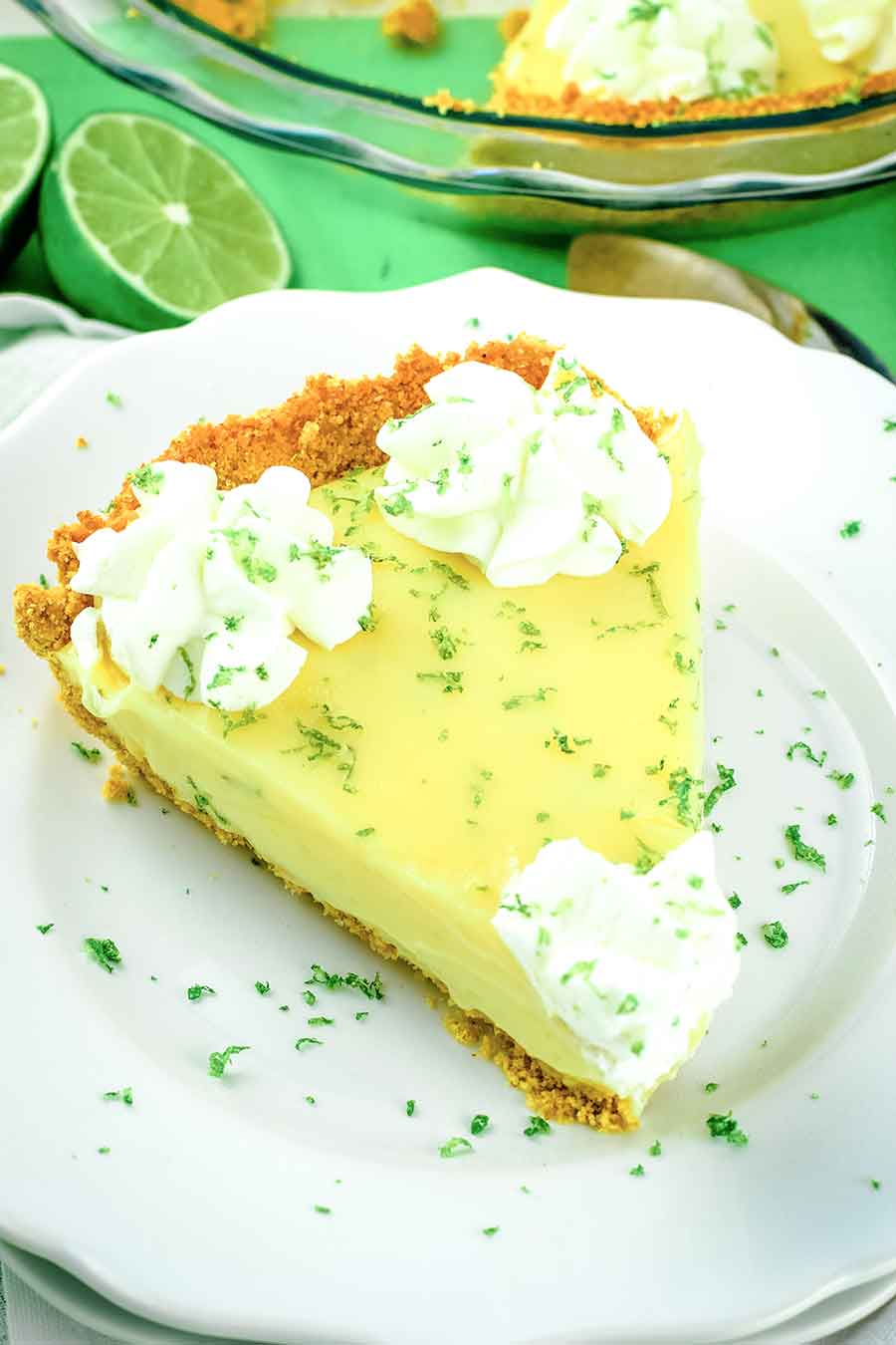 A slice of the Best Key Lime Pie topped with whipped cream and lime zest