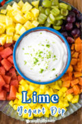 A sweet lime yogurt in a serving bowl on a fruit filled platter.
