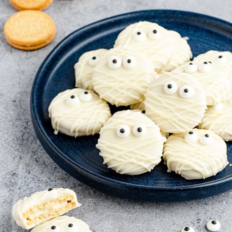 White chocolate oreo mummy cookies on a dark plate.