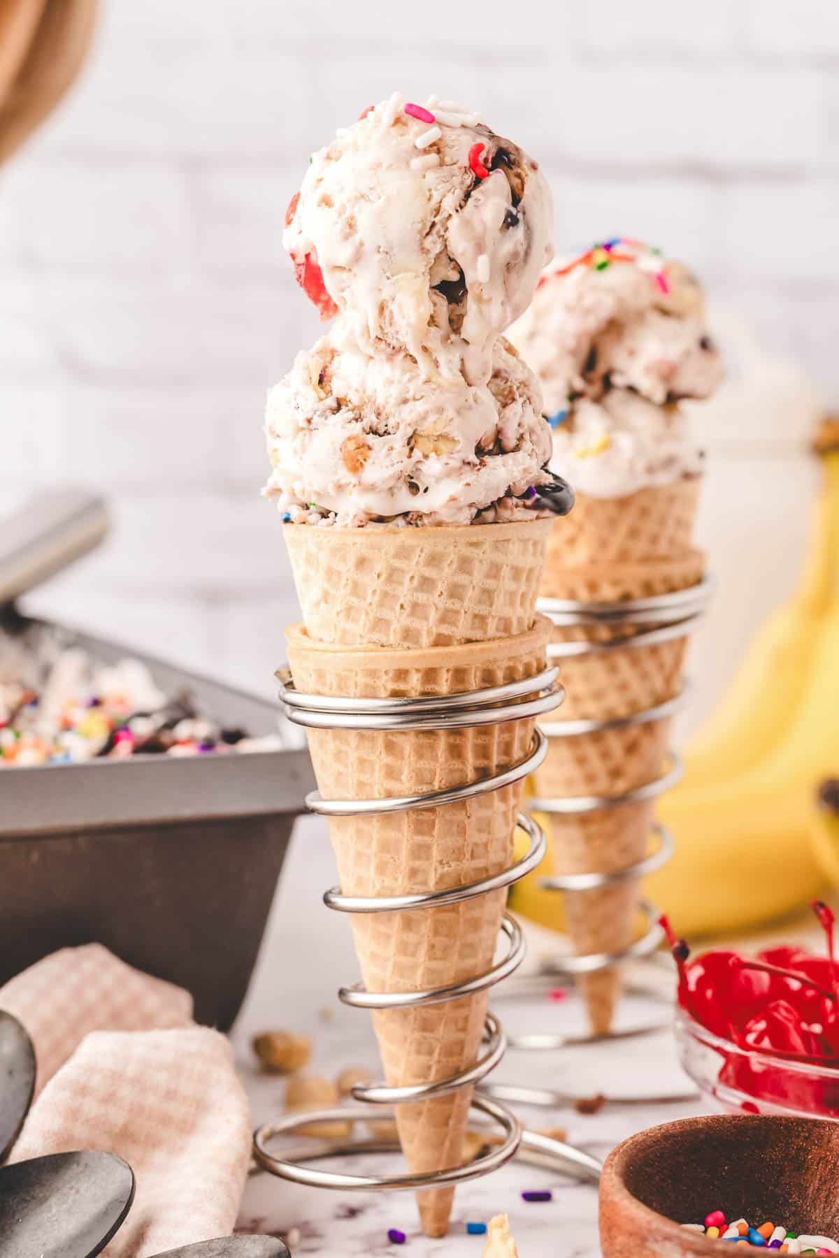 Ice cream cones filled with banana split ice cream in cone holders.