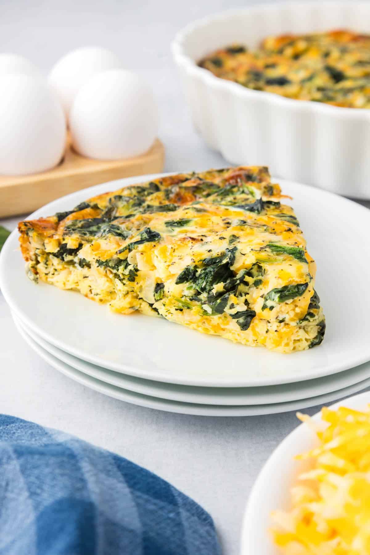 A slice of crustless spinach quiche on a white plate.