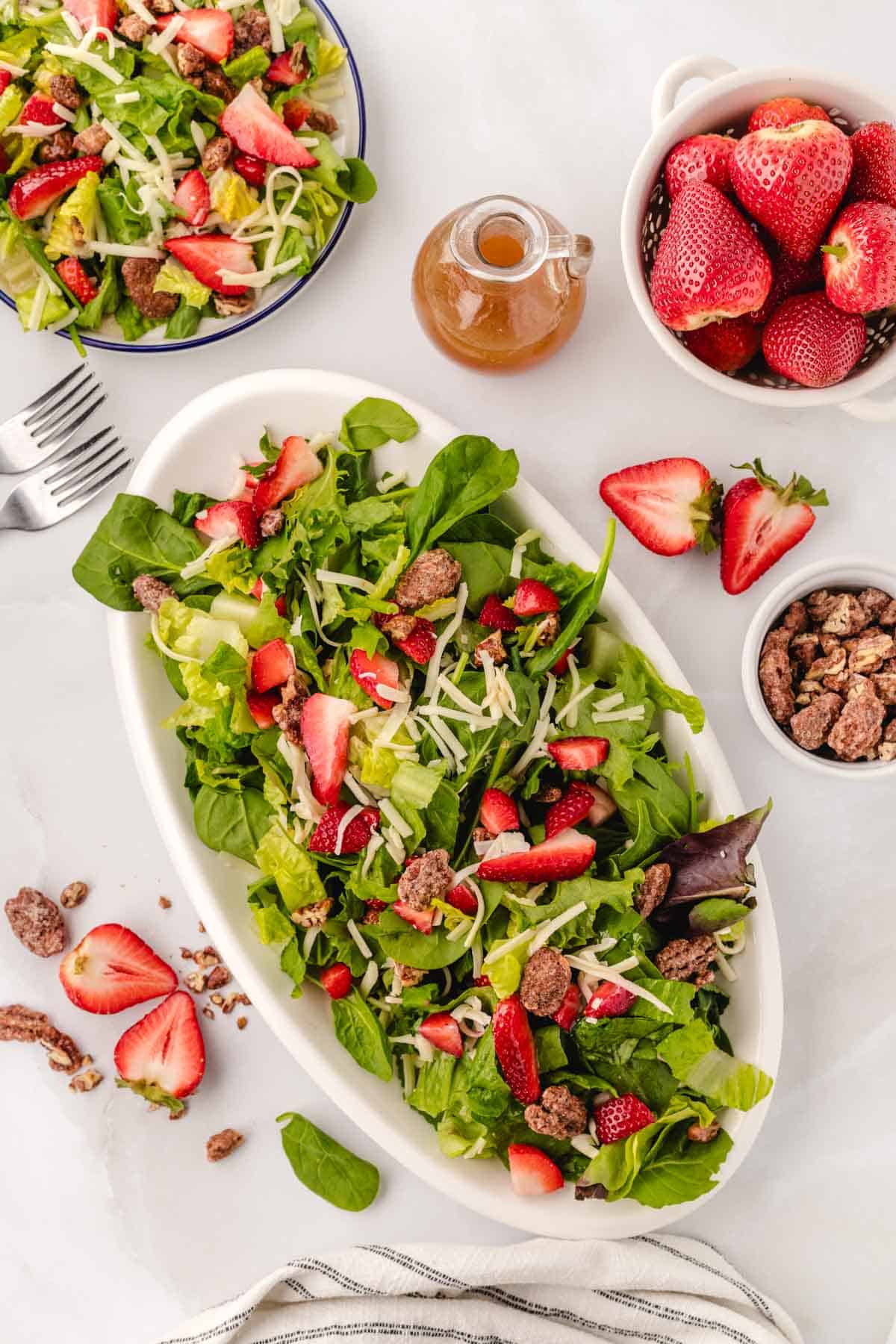 A white serving platter with a strawberry salad.