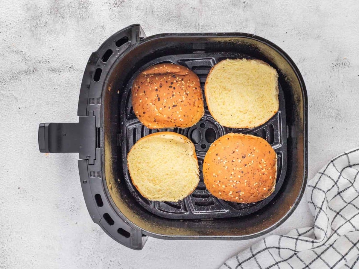 Hamburger buns in an air fryer being toasted.