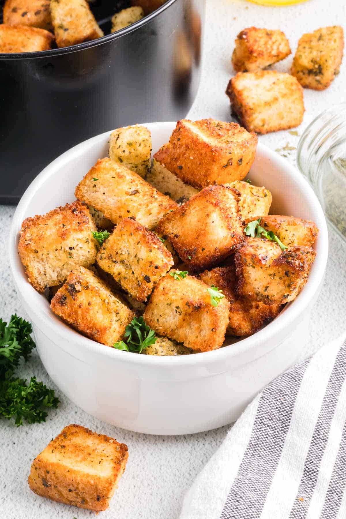 Homemade croutons in a white bowl garnished with fresh parsley.