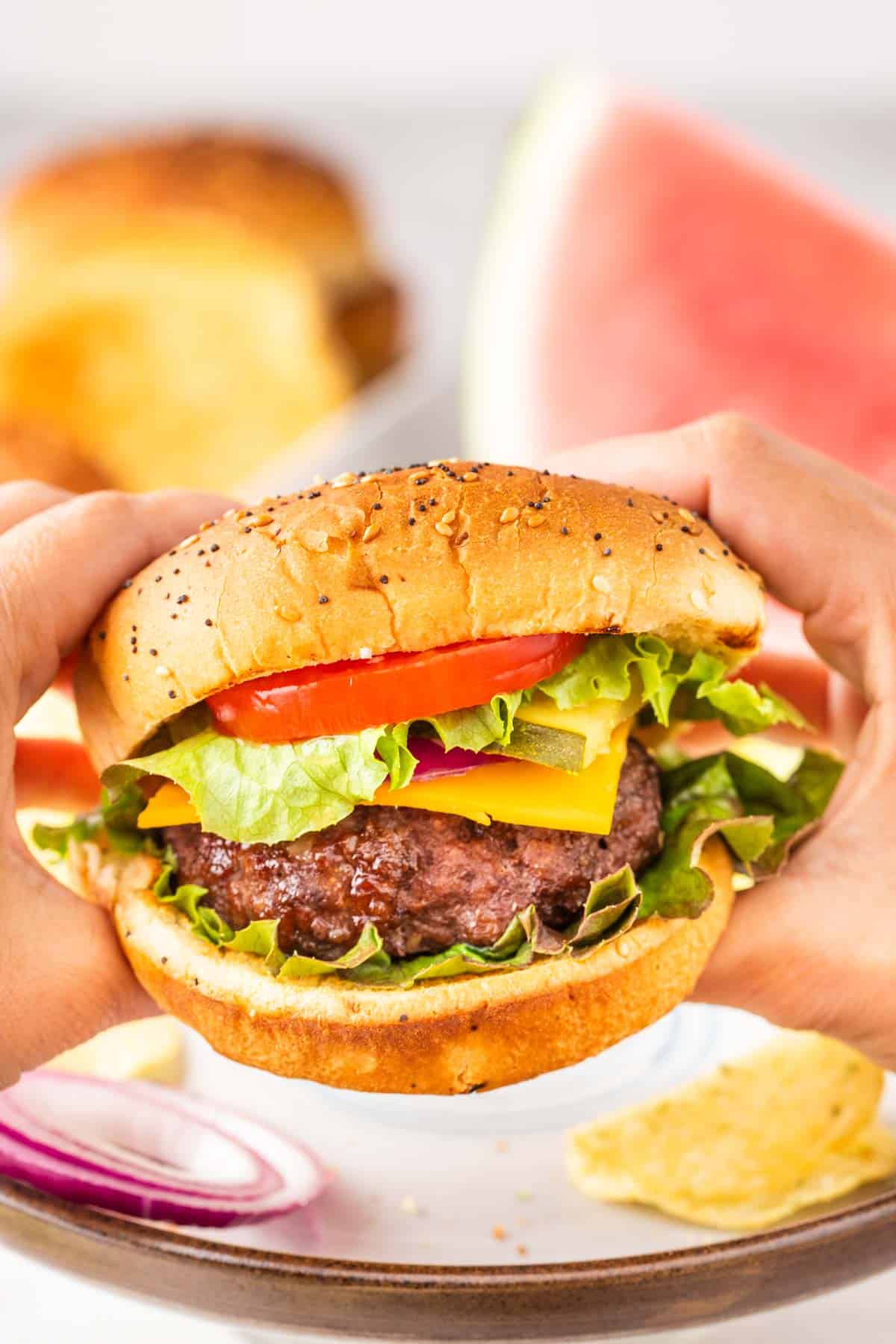 Two hands holding a juicy hamburger that was cooked in the air fryer.