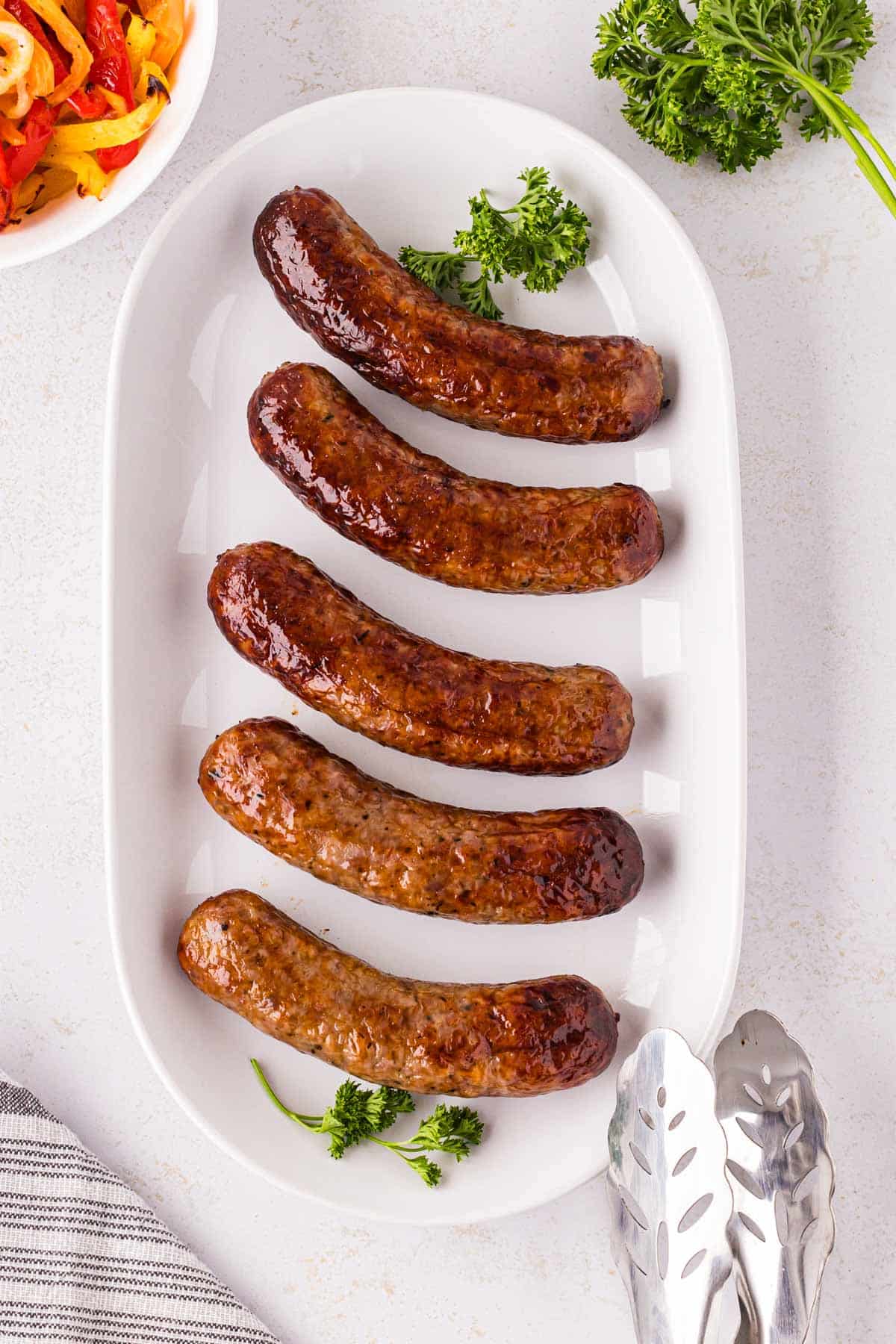 A white serving plate filled with Italian sausages.