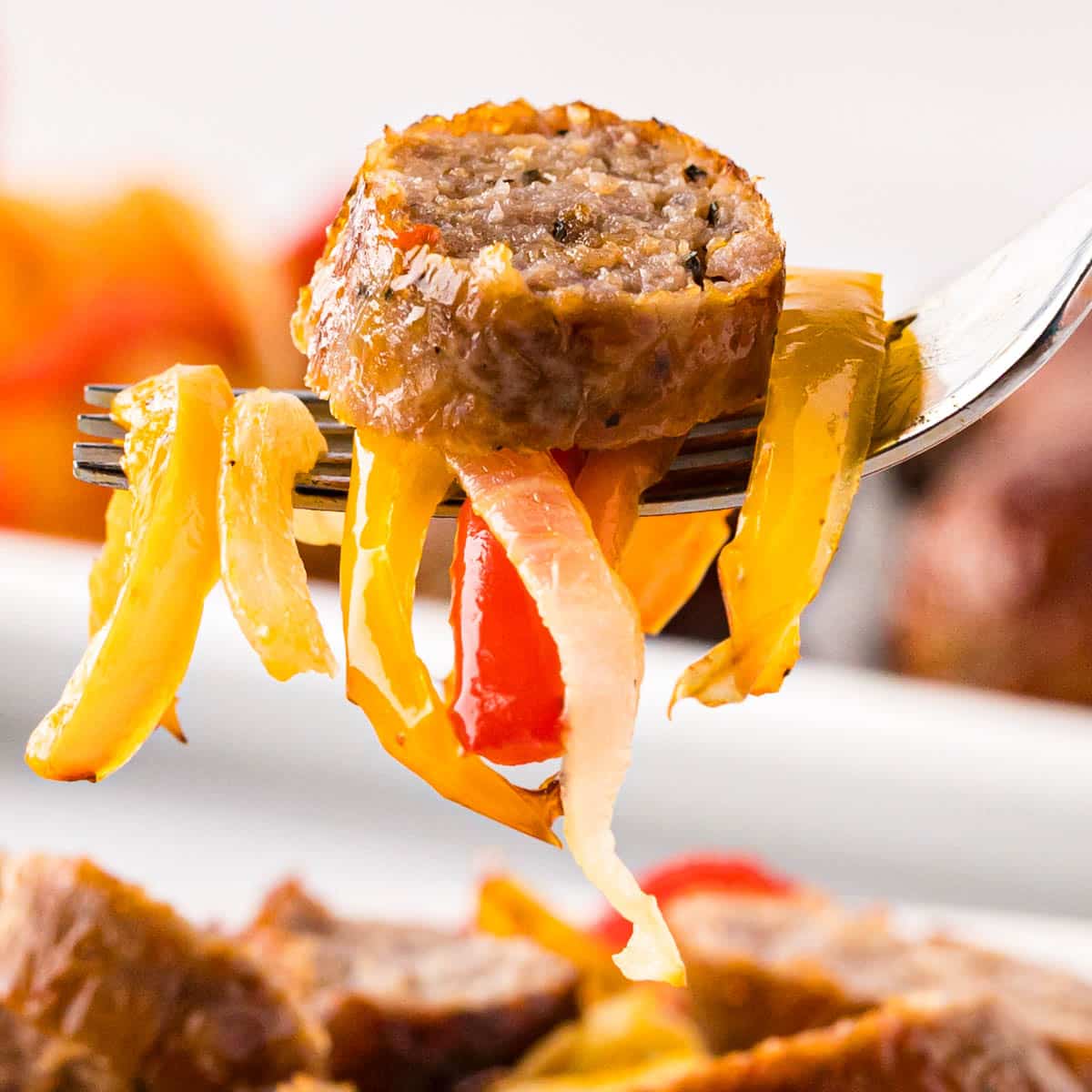 A fork with a slice of Italian sausage and peppers.