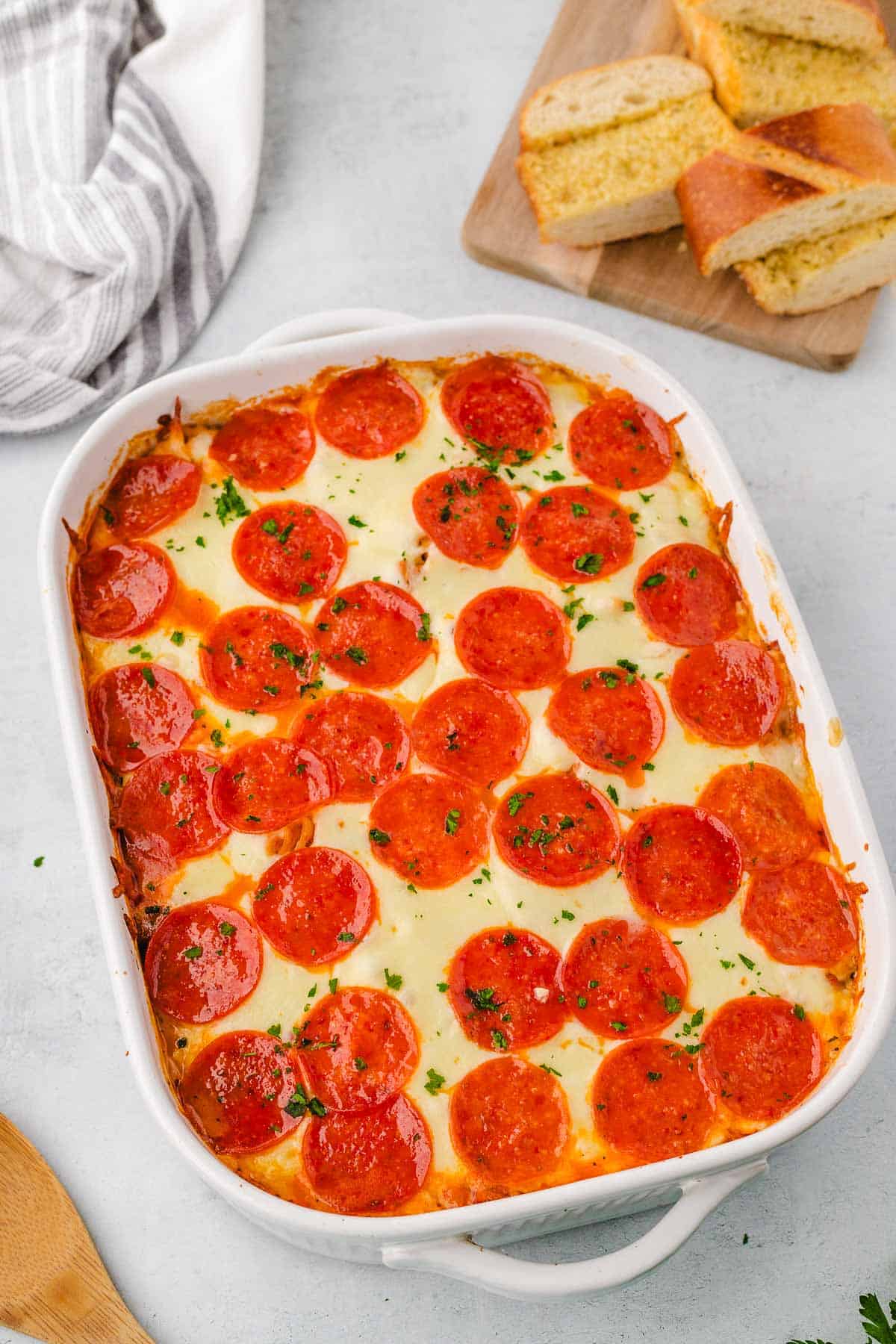 A white casserole dish filled with baked pizza pasta.