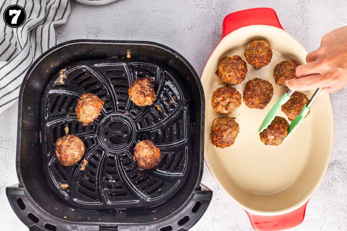 Removing cooked meatballs from the air fryer.