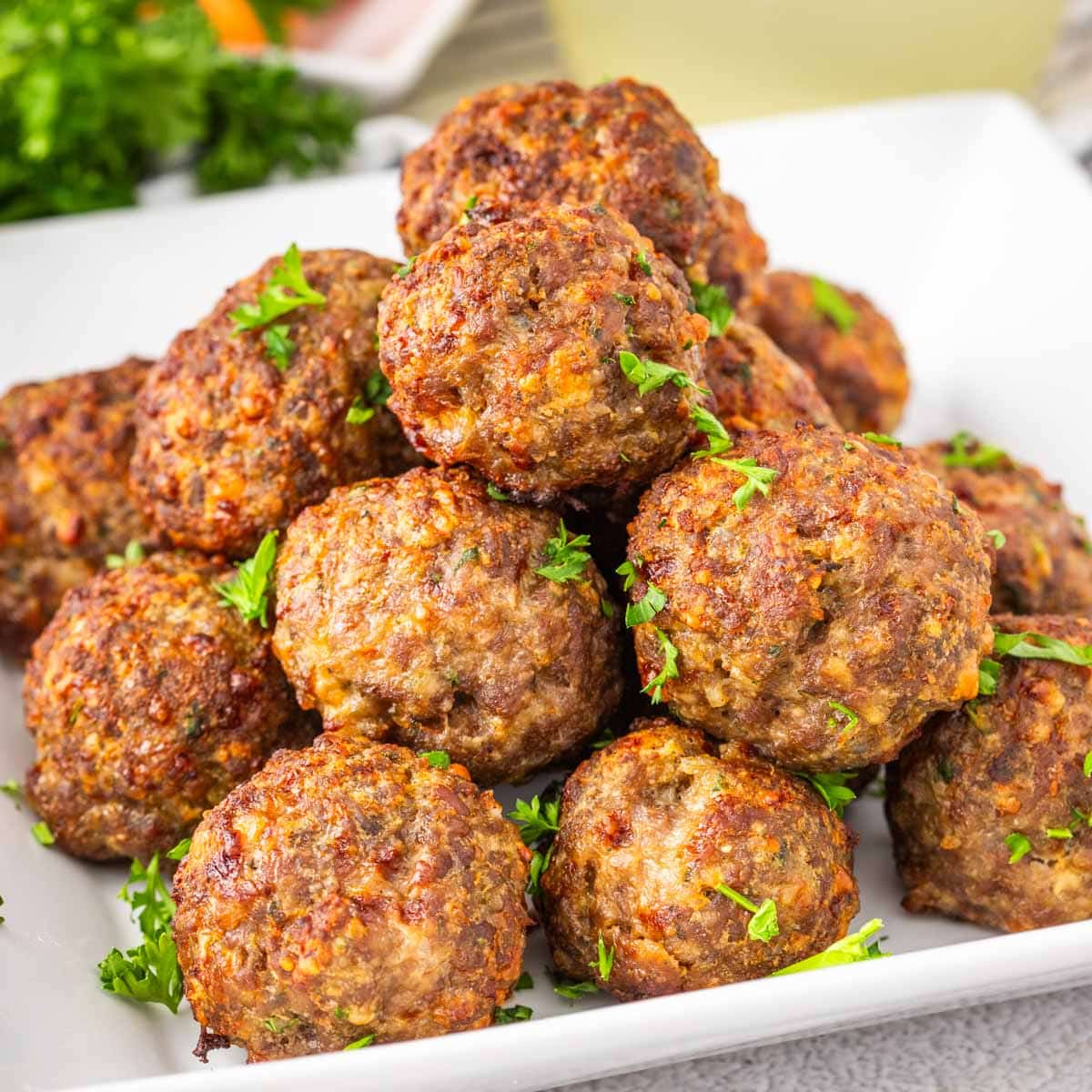 Air fryer meatballs on a white plate garnished with parsley.