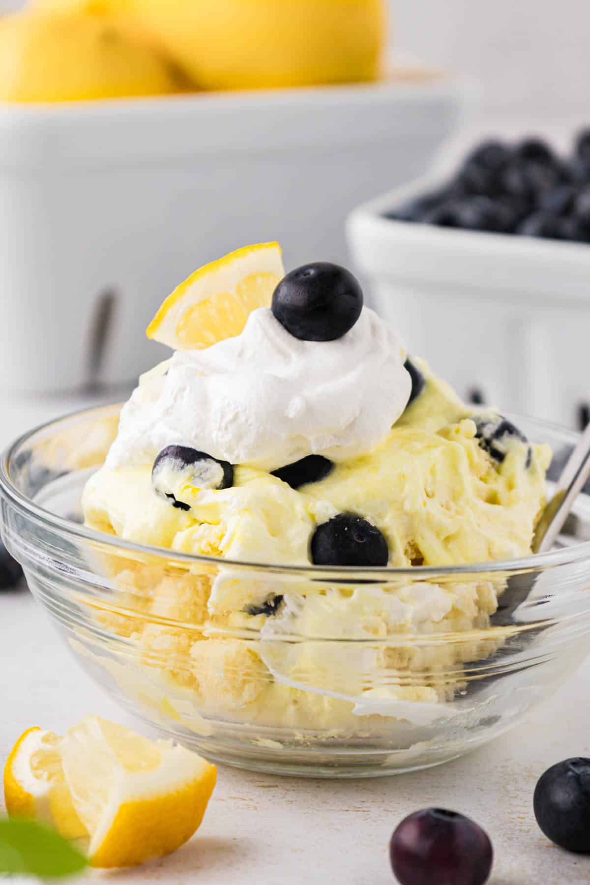 An individual serving of blueberry lemon trifle in a glass dessert bowl.