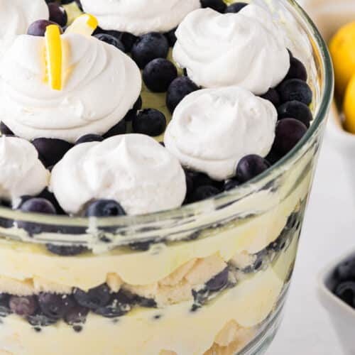 A lemon blueberry trifle in a glass trifle bowl with a stand.