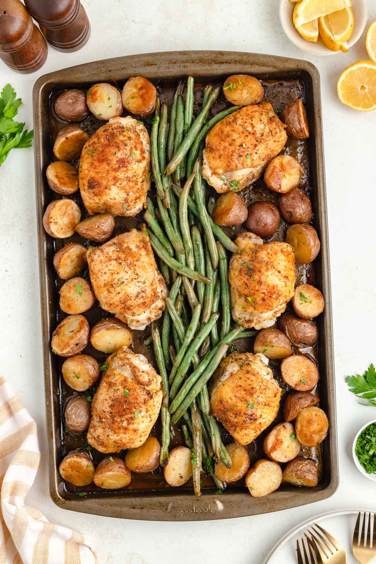 An overhead view of a sheet pan, chicken, potatoes, and green bean dinner.