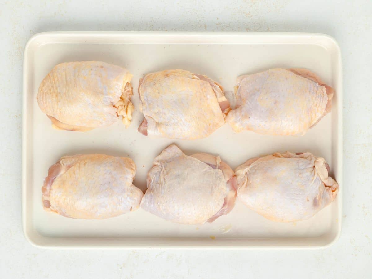 A pan with chicken thighs that were patted dry with a paper towel.