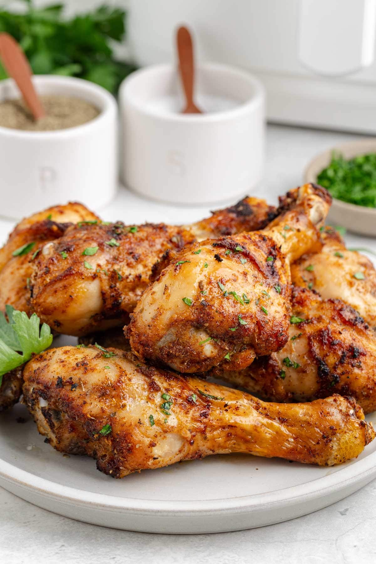 A beige serving plate filled with perfectly crispy air fryer chicken drumsticks.