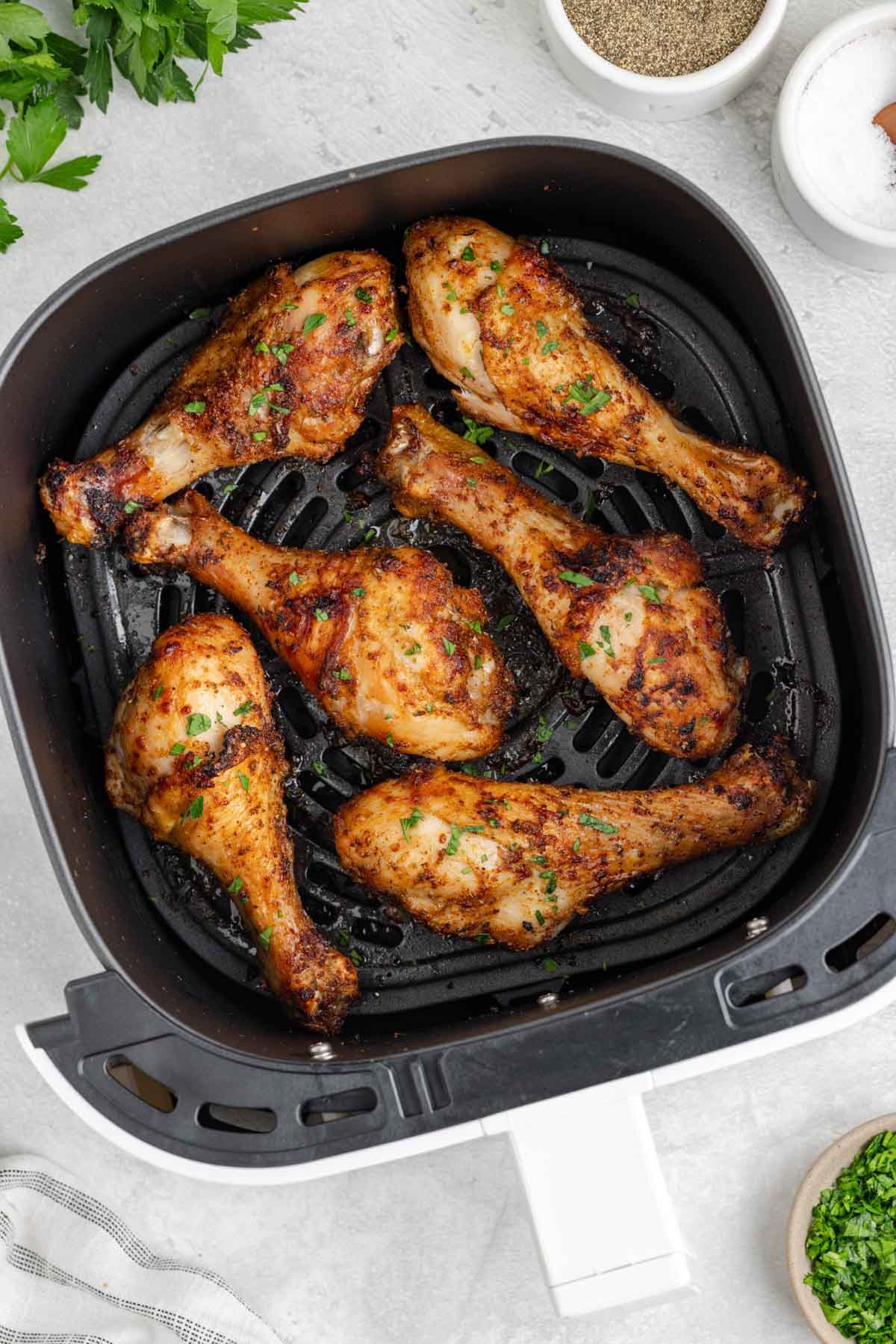 An air fryer basket with perfectly seasoned crispy cooked chicken legs.