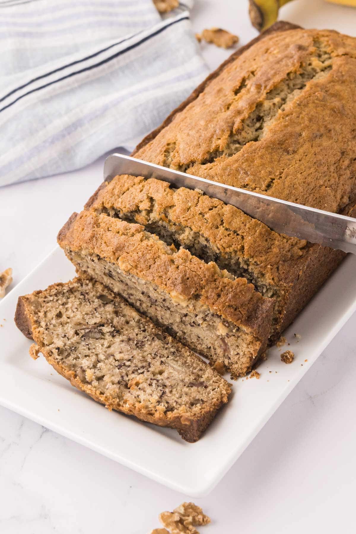 Serrated knife, slicing a loaf of banana bread made with buttermilk.