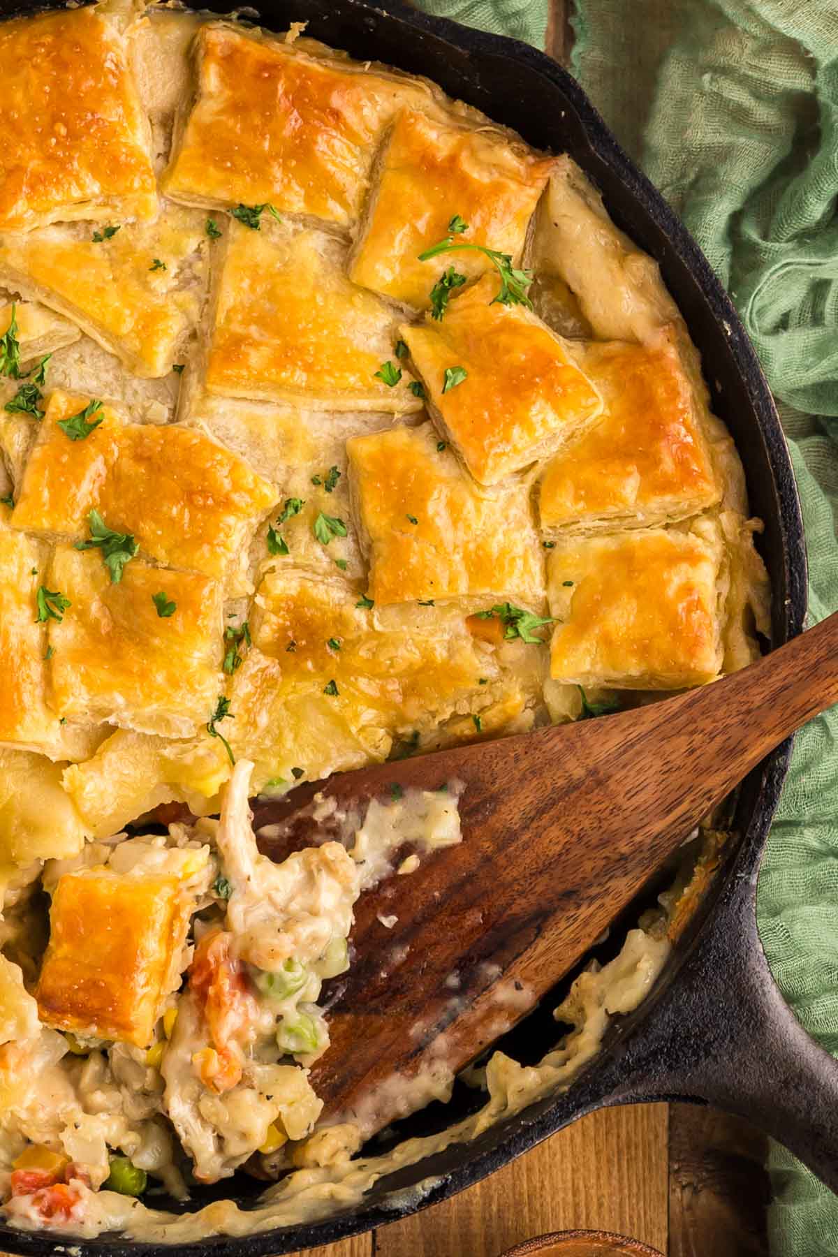 A wooden spoon scooping out a serving of chicken pot pie.