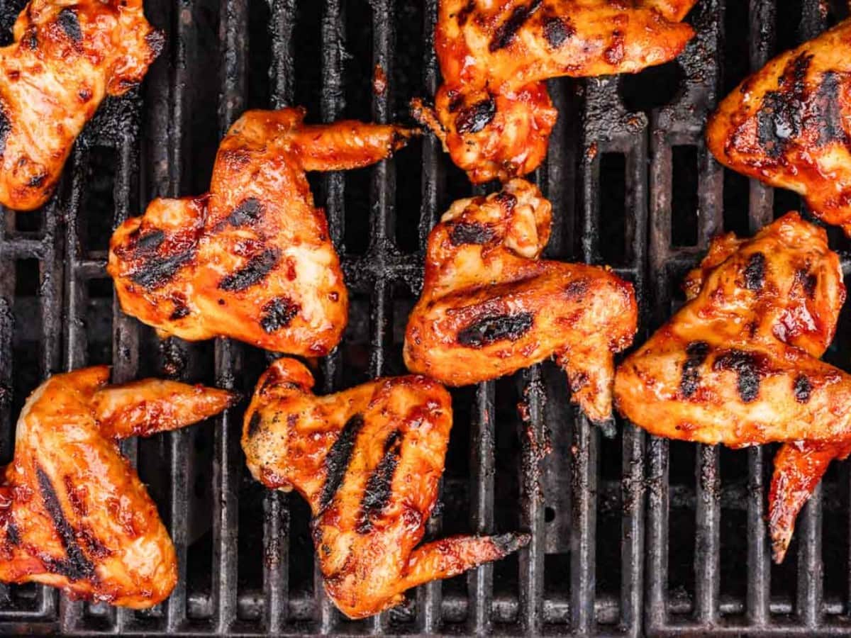 Wings on the grill with honey chipotle bbq sauce on them.