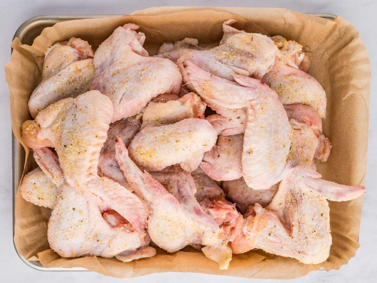 Wings seasoned with garlic salt on a tray.