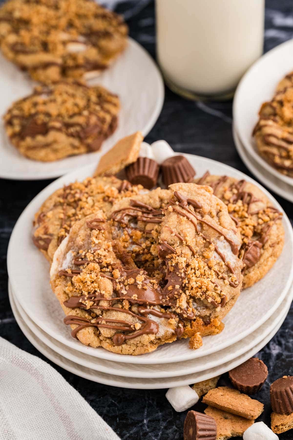 Peanut butter s'mores cookies, drizzled with Reese's chocolate drizzle, and graham cracker topping on a white plate.