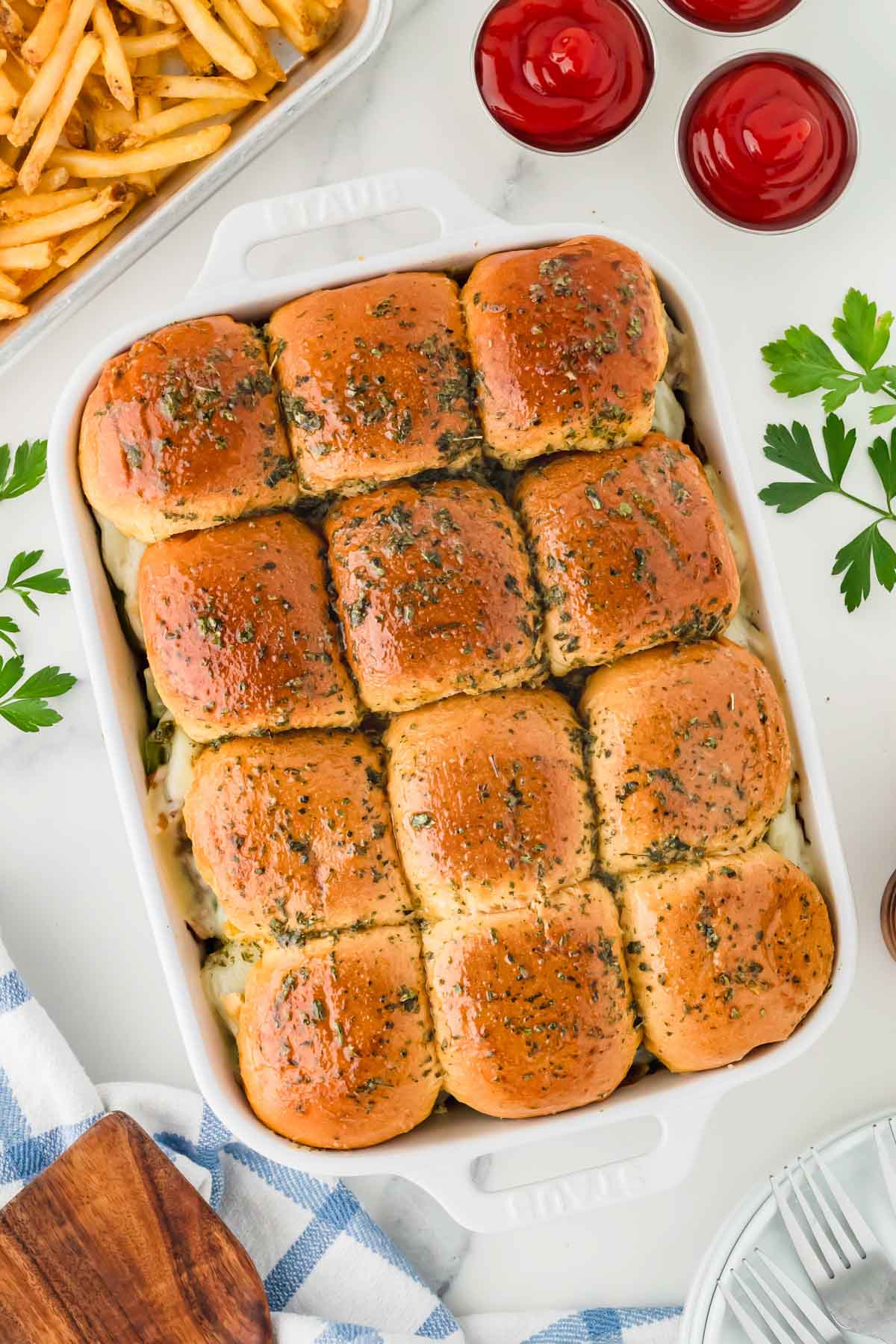 A white baking dish full a Philly cheesesteak sliders.