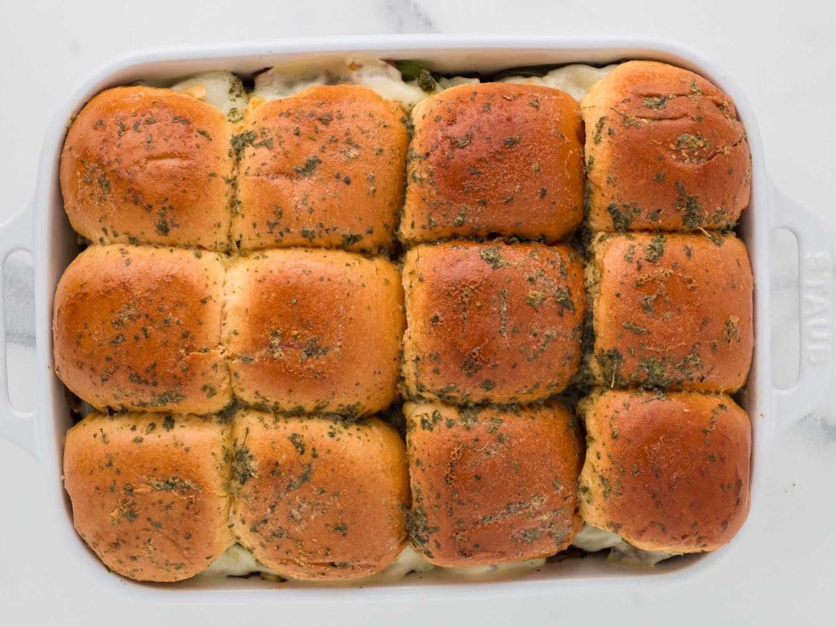 A tray of sliders with a buttery garlic topping after being baked.