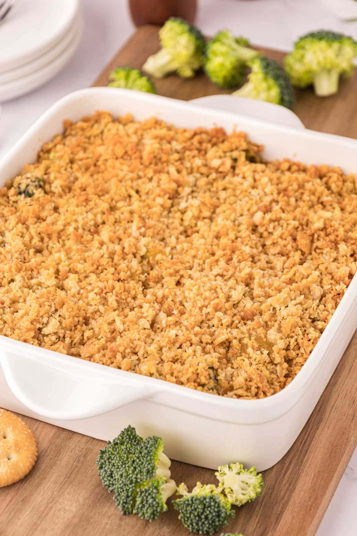 A casserole dish with southern broccoli casserole topped with a cracker crust in a white baking dish.