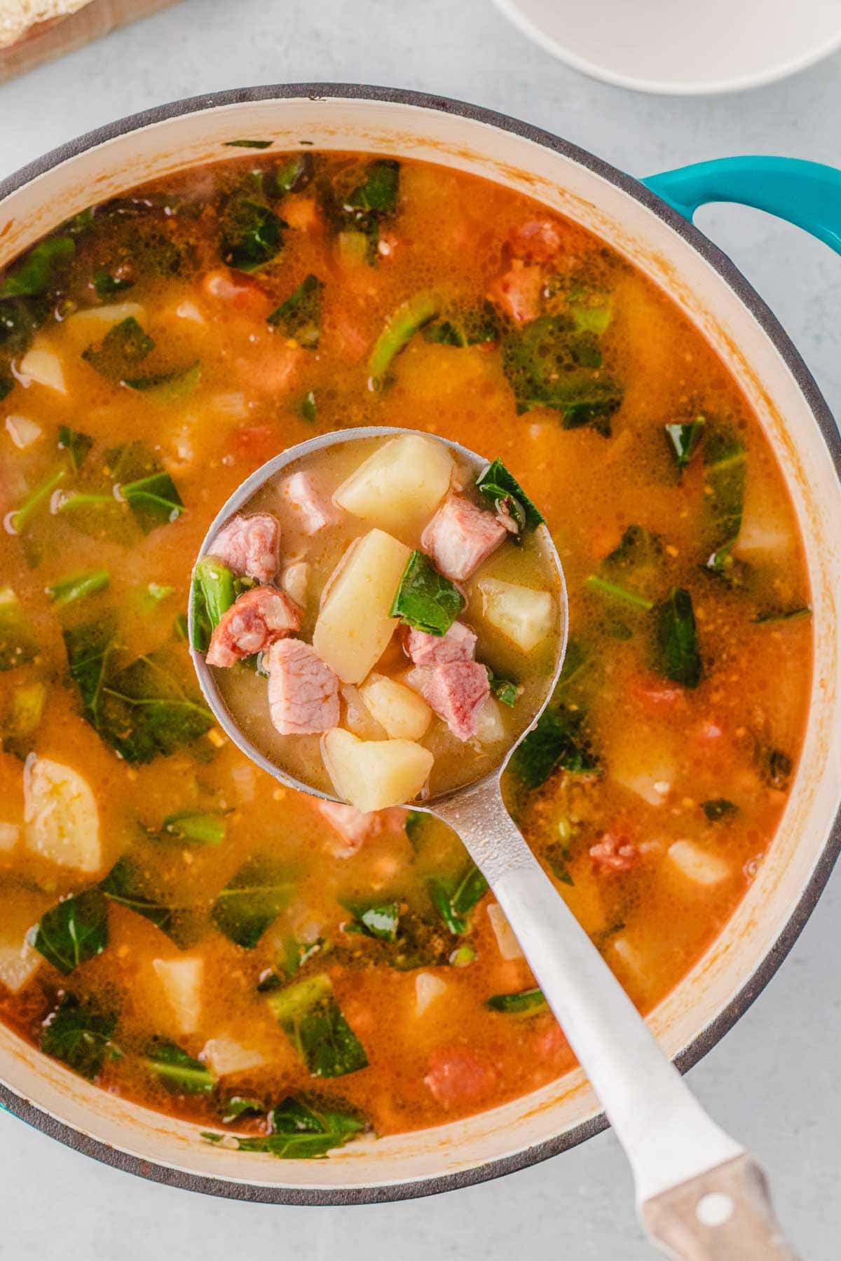 A blue dutch oven pot with turnip green soup.