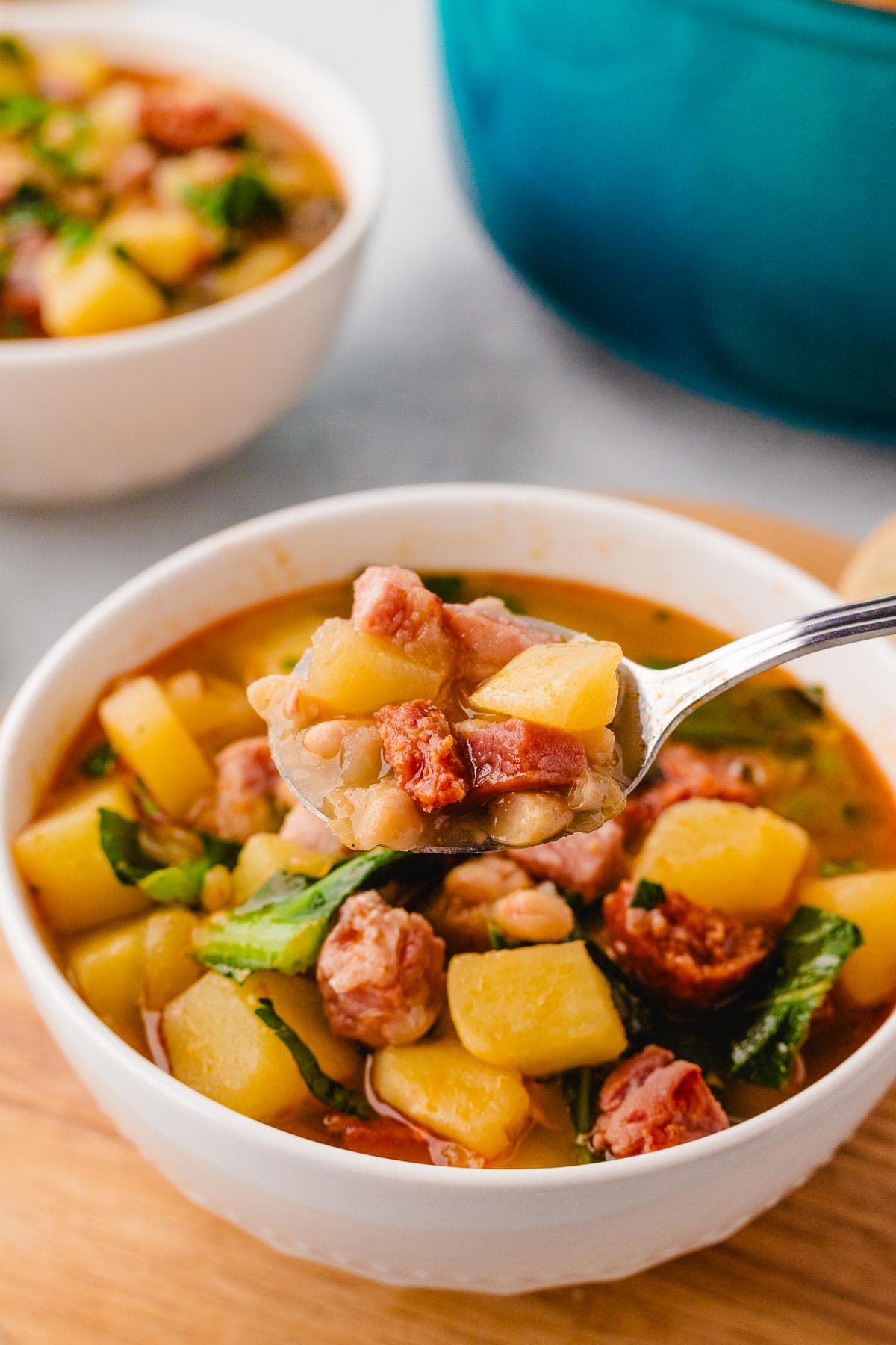 A spoon remove a bite of turnip green soup.