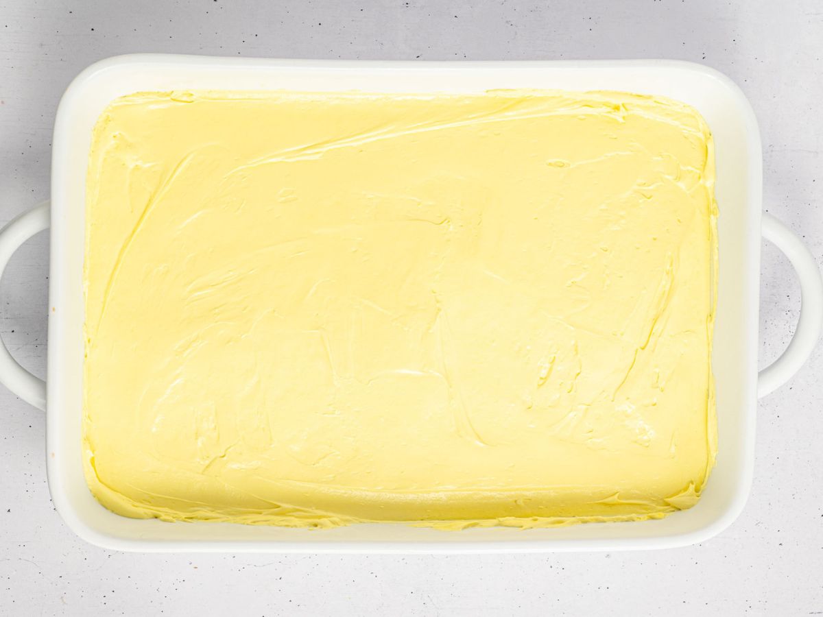 Yellow cheesecake layer on top of crust layer in a baking dish.