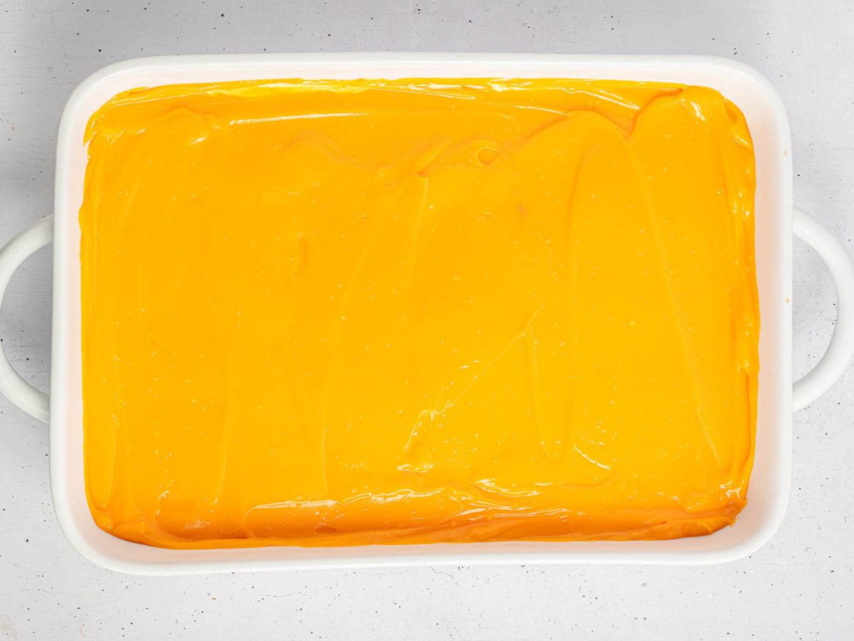 Orange pudding layer on top in a baking dish.