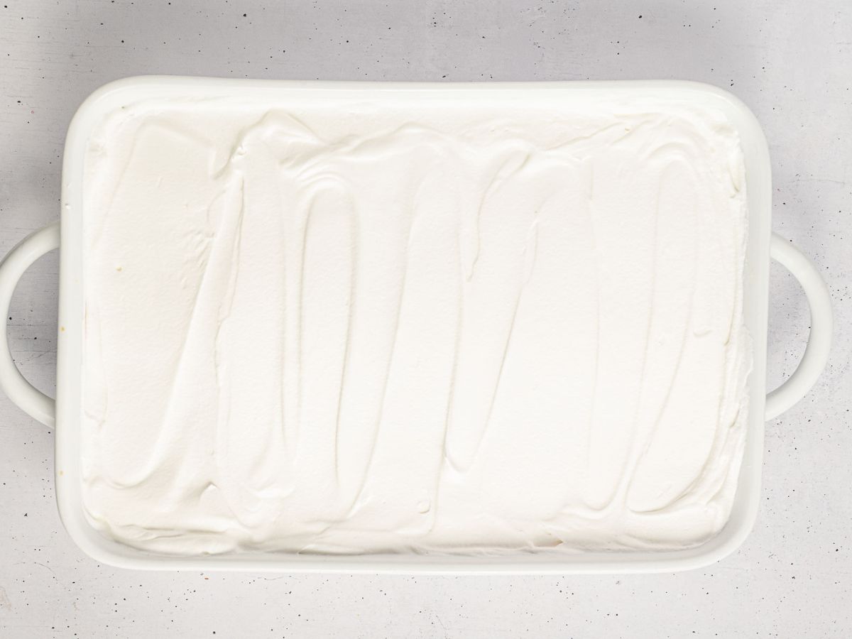 Whipped topping added on top of the candy corn lush in a baking dish.