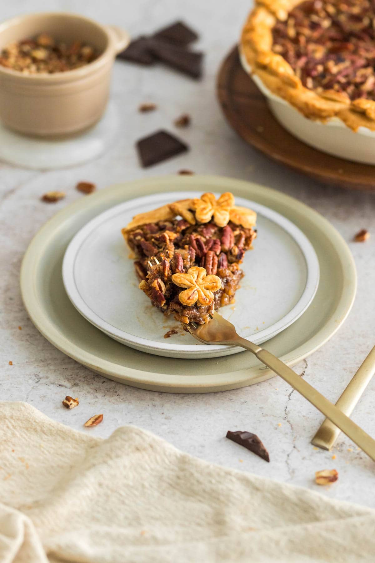 A slice of pecan pie with chocolate on a white plate.