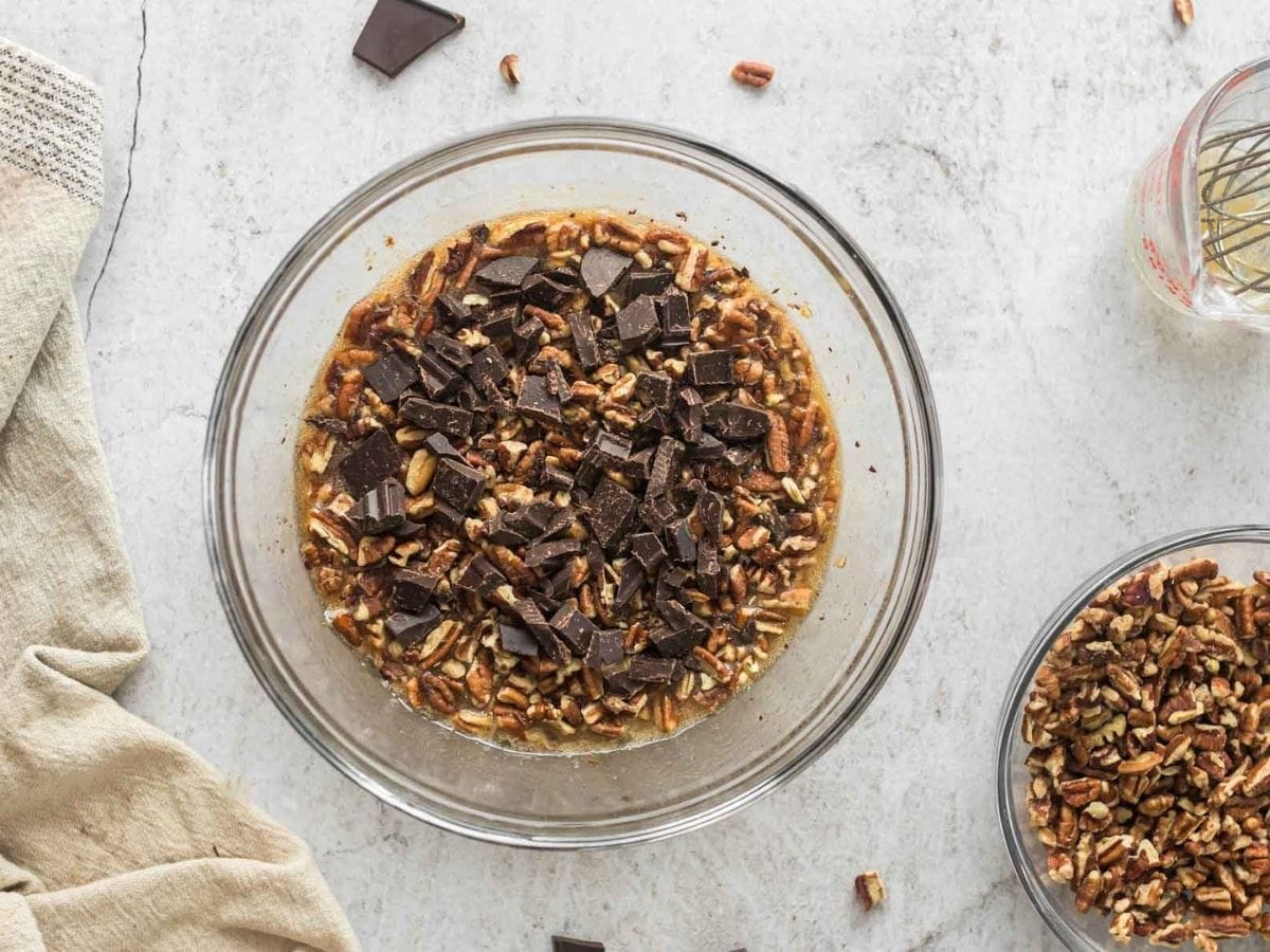 Nuts and chocolate added to pie filling in a bowl.