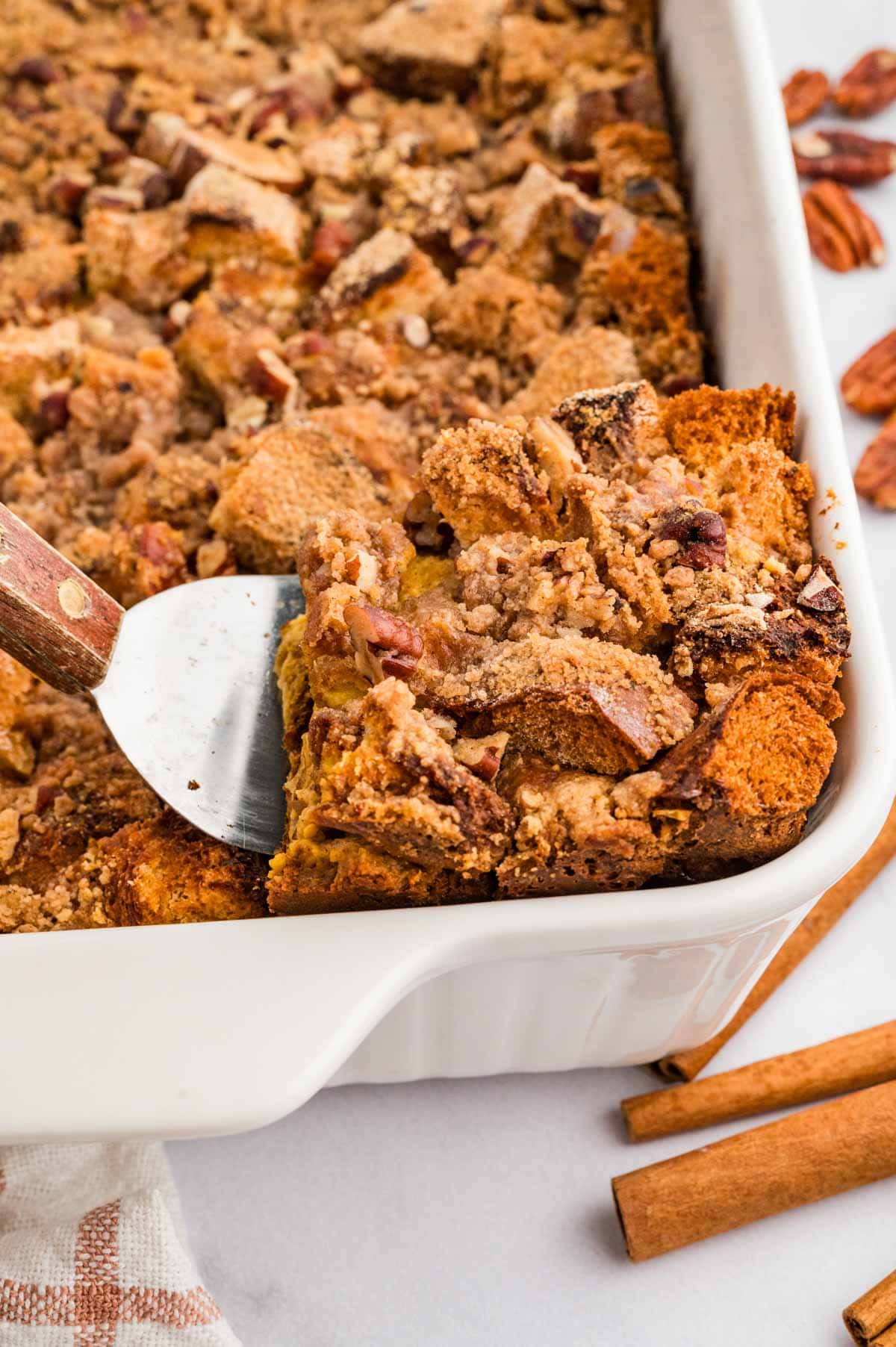 Spatula taking out a square piece of pumpkin French toast casserole from a baking dish.