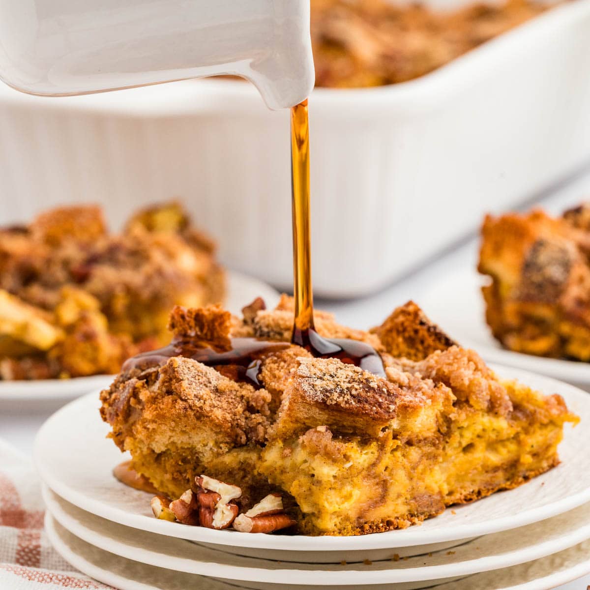 Pouring syrup on top of a slice of pumpkin French toast casserole.