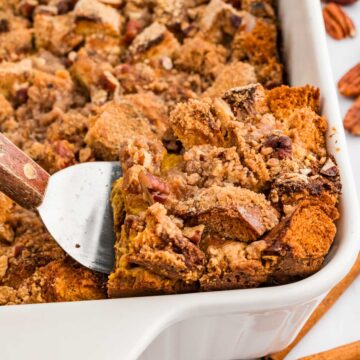 Spatula taking a piece of the pumpkin French toast casserole from a baking dish.