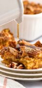 A beautiful image of a white carafe pouring syrup on the pumpkin French toast casserole serving.