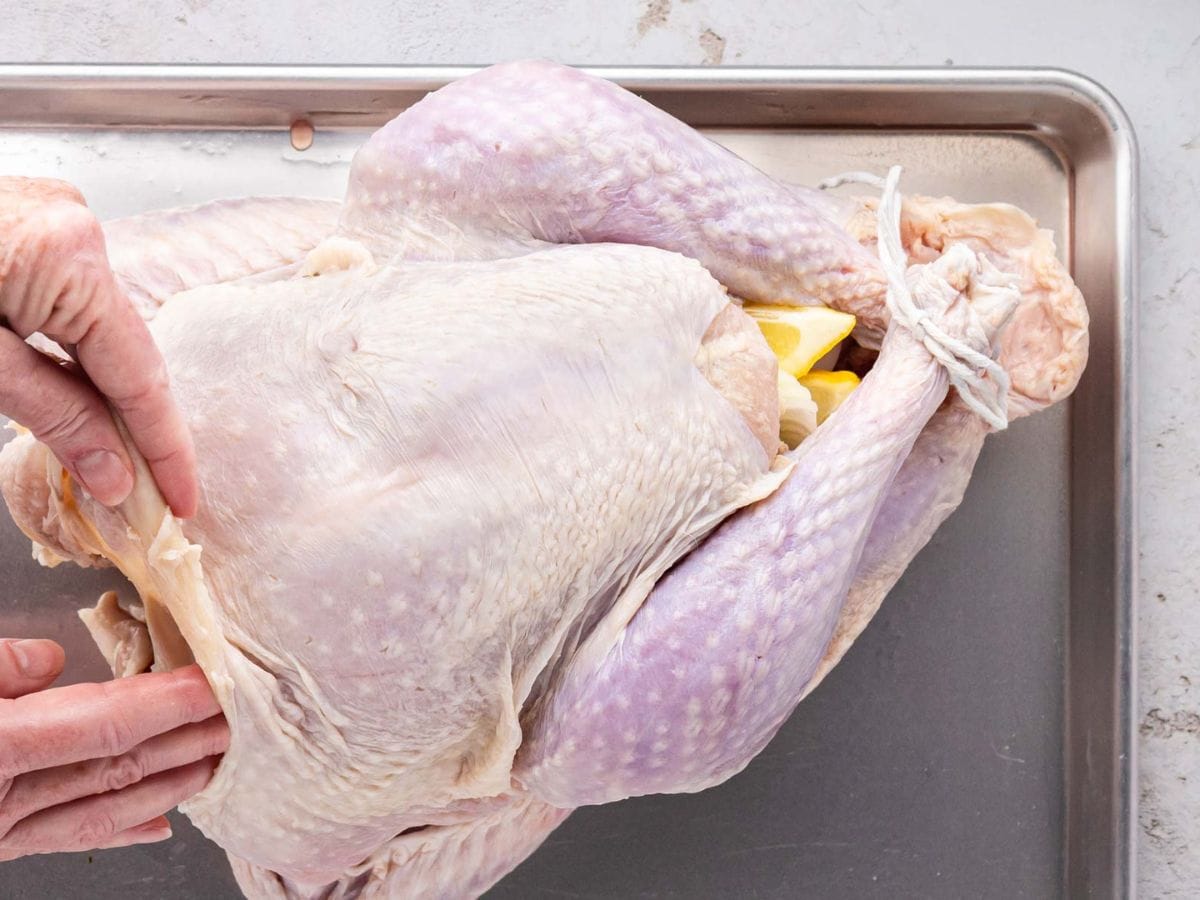 Lifting skin from around the turkey breast with fingers.