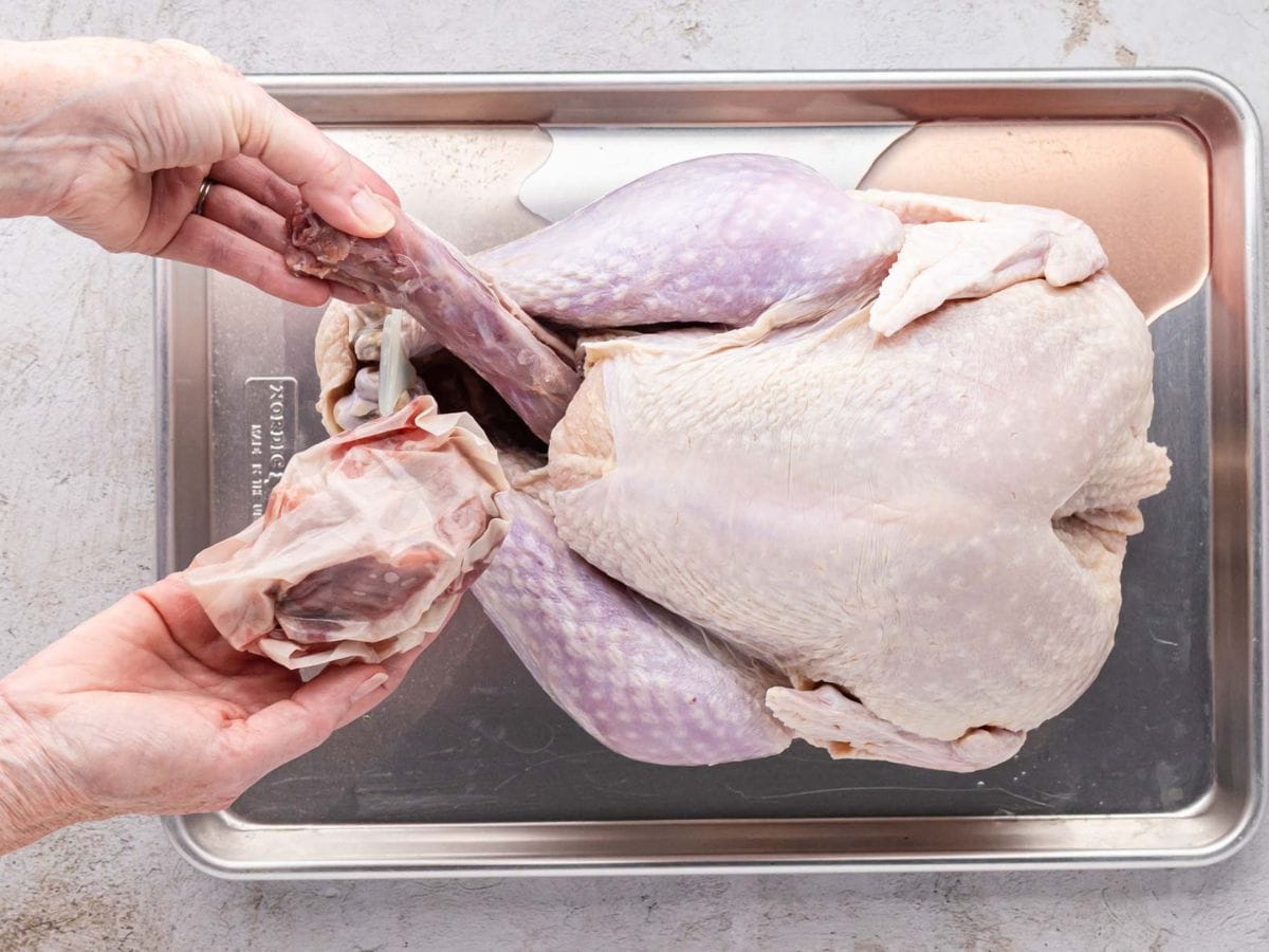 Removing the neck and gizzards from the inside of a whole turkey.