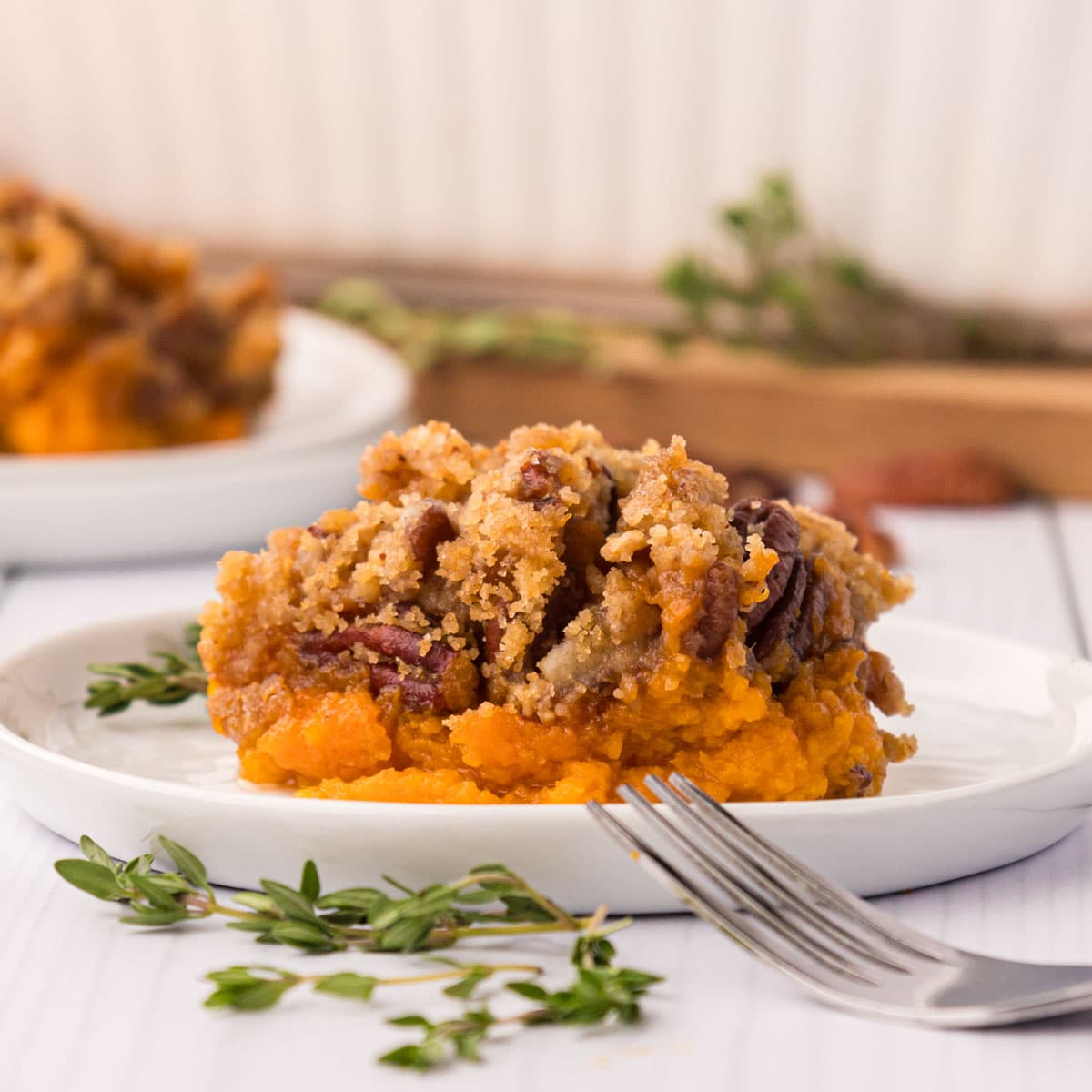 A white plate with a scoop of sweet potato casserole with pecan crumb topping.