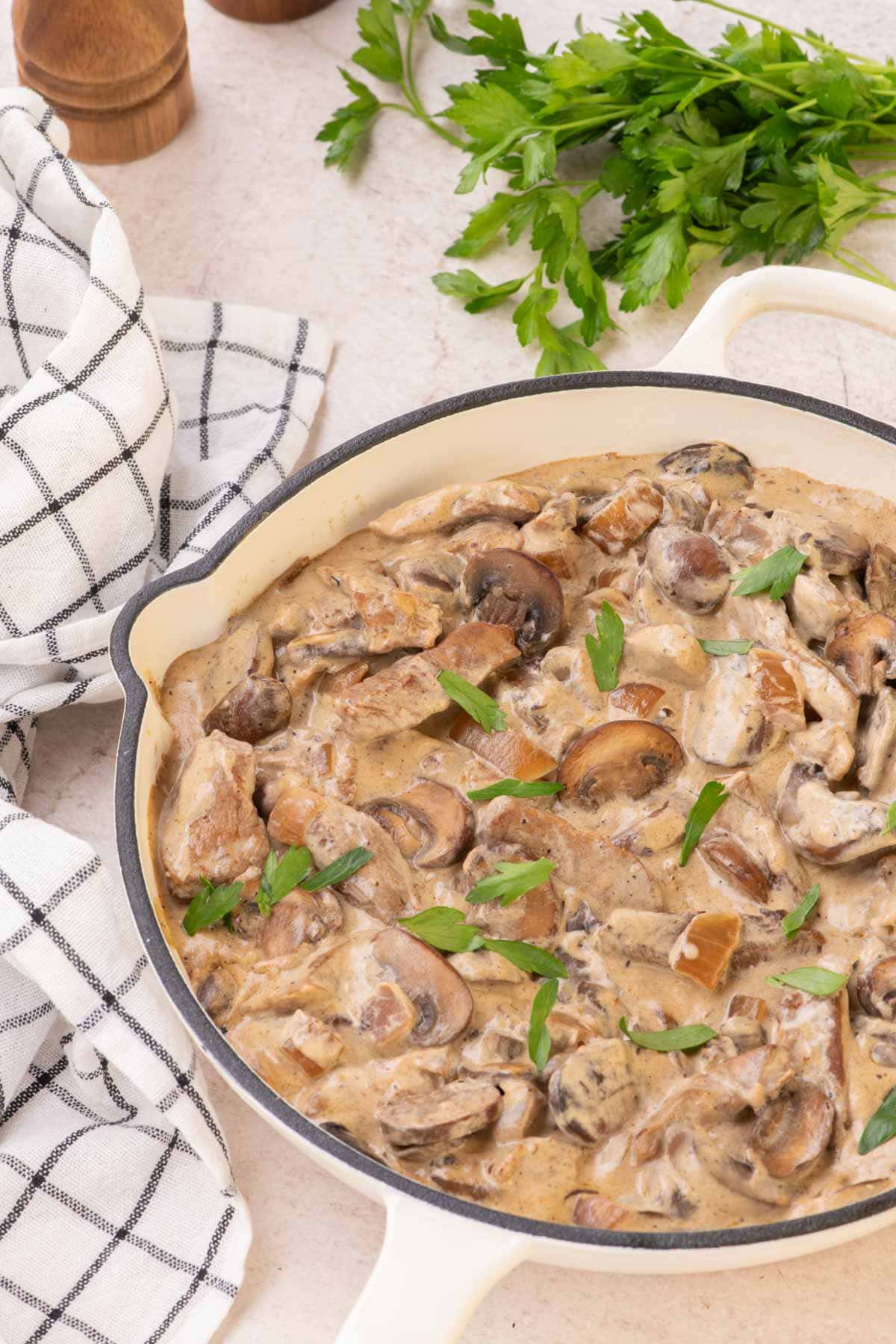 Beef stroganoff in a white skillet with parsley on top.