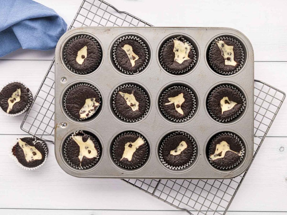 Black bottom cupcakes after being cooked in the muffin tin and placed on a cooling rack.