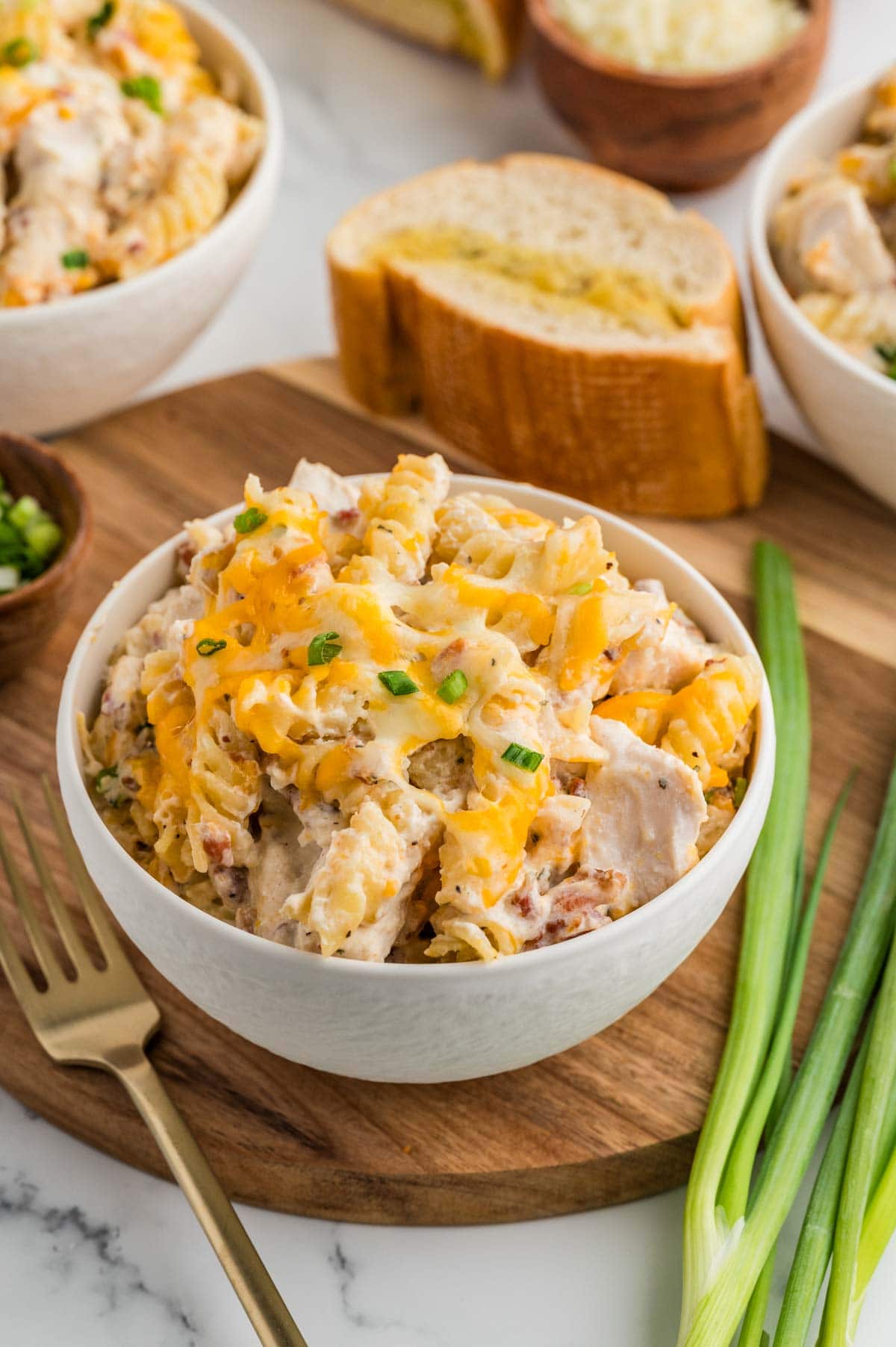 Serving of crack chicken casserole in a bowl with some garlic bread in the background.