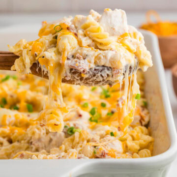 Removing a scoop a cheesy crack chicken pasta from the serving dish.