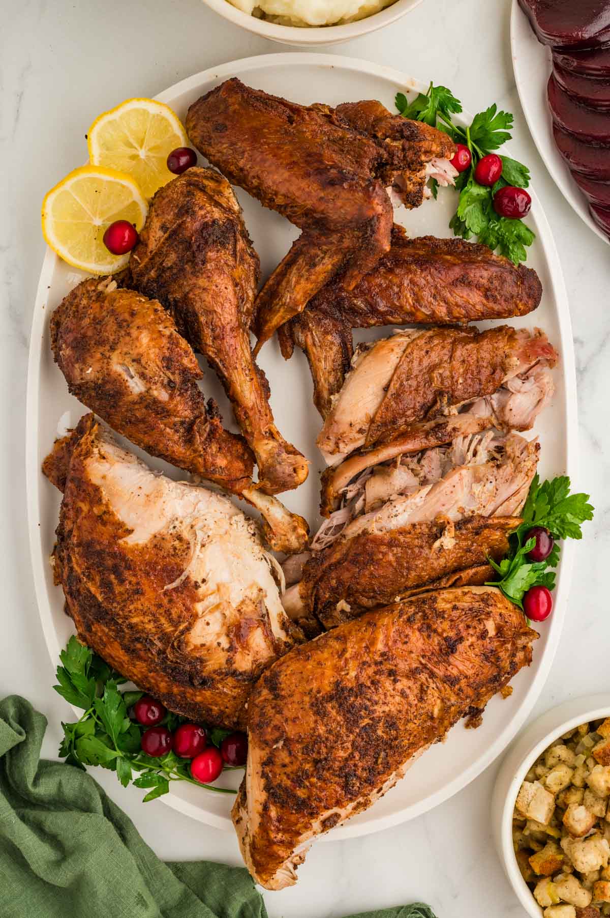 A deep-fried turkey cut into pieces set on a white serving plate.