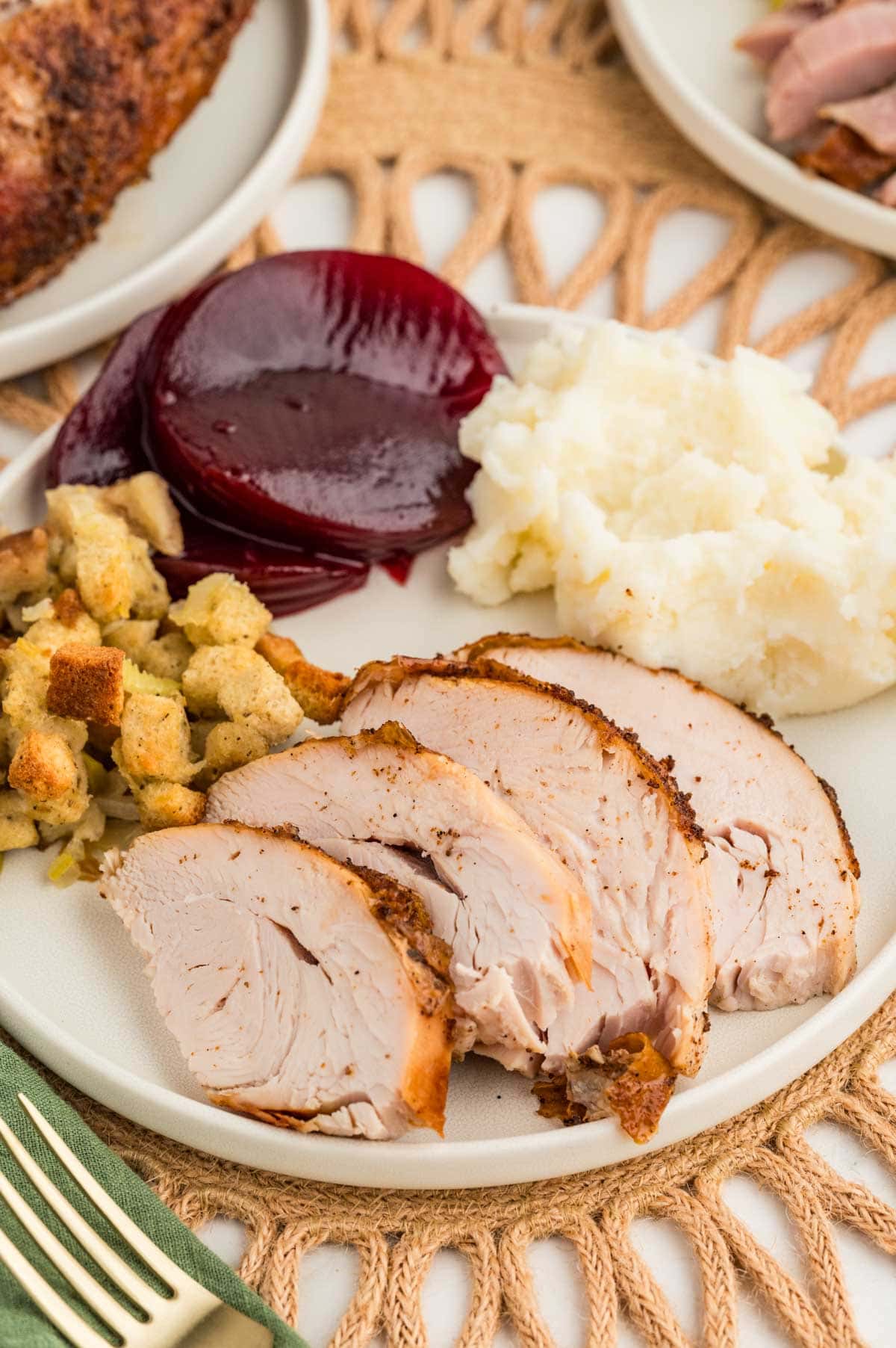 Sliced turkey, stuffing, cranberry sauce and mashed potatoes on a plate.